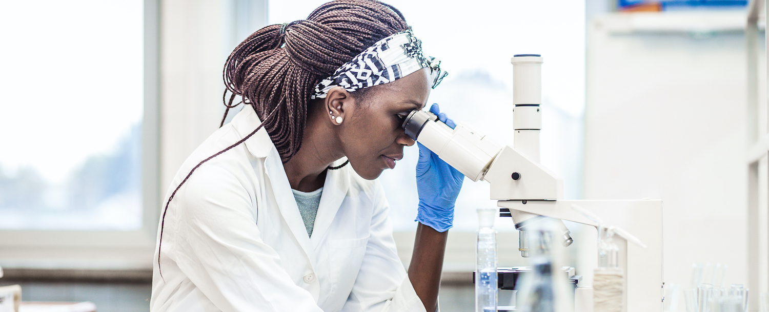 College student looking into microscope in the Shera Laboratory